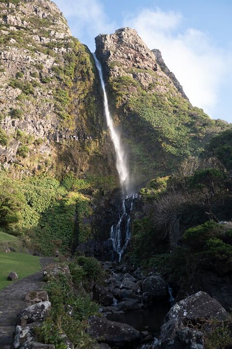 Tall waterfall dropping down a green cliff