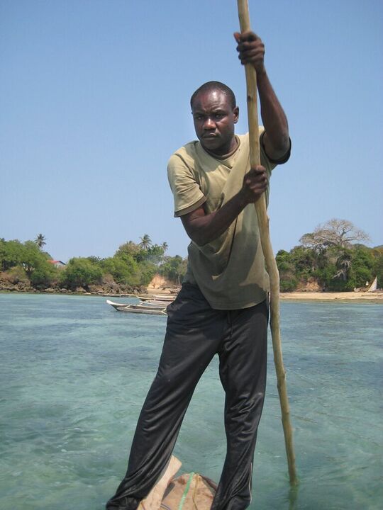 Boatman poling across turquoise shallows