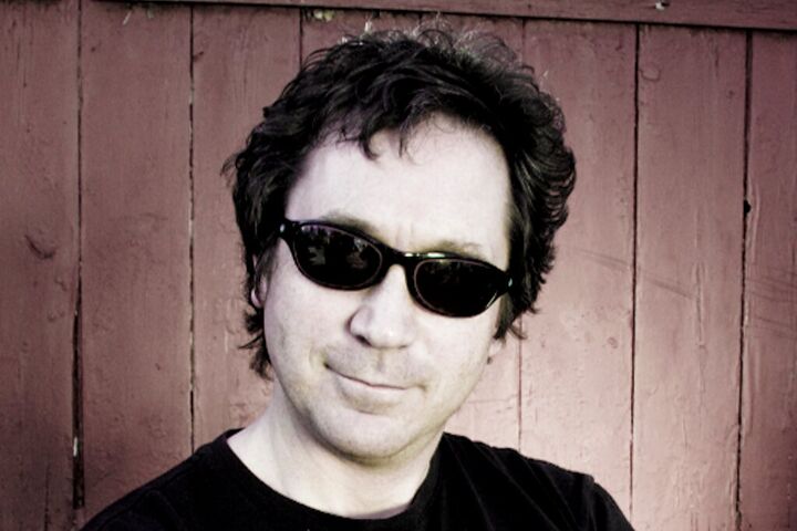 Musician in dark sunglasses against a wooden wall