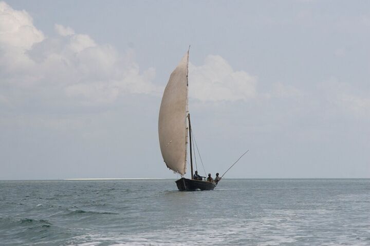 Single dhow sailing on a grey sea