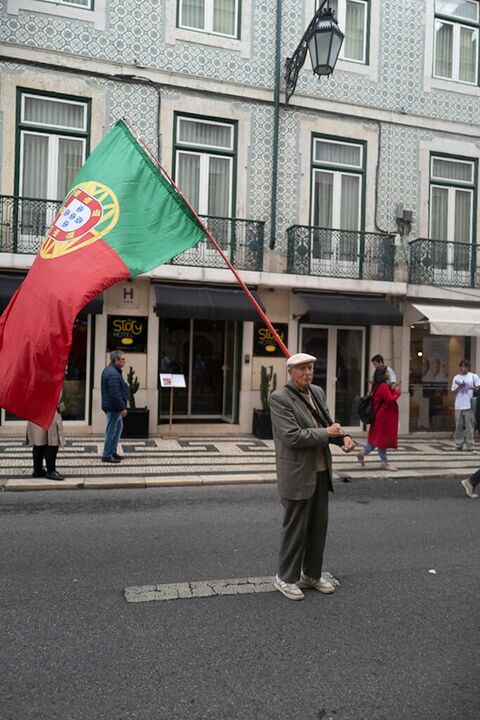 Man holding a large Portuguese flag in the street