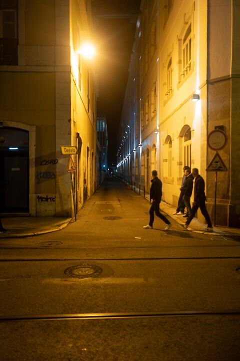 Figures crossing a lamplit street at night