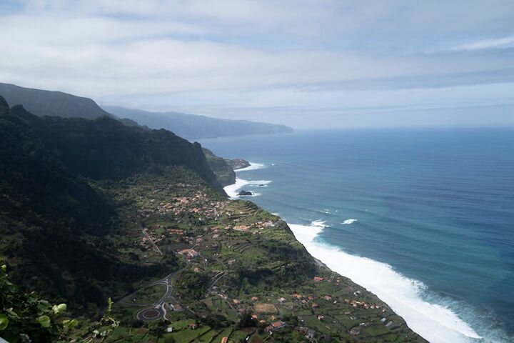 Surf along a steep green coastline