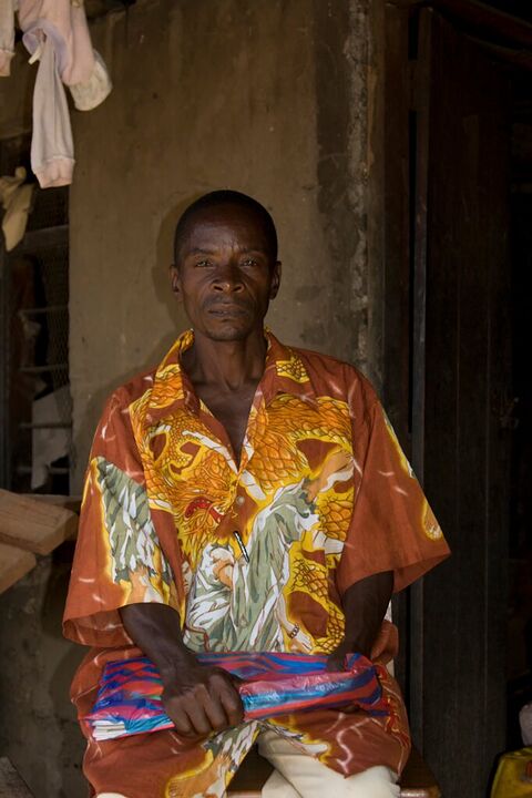 Man in an orange patterned shirt seated in a doorway