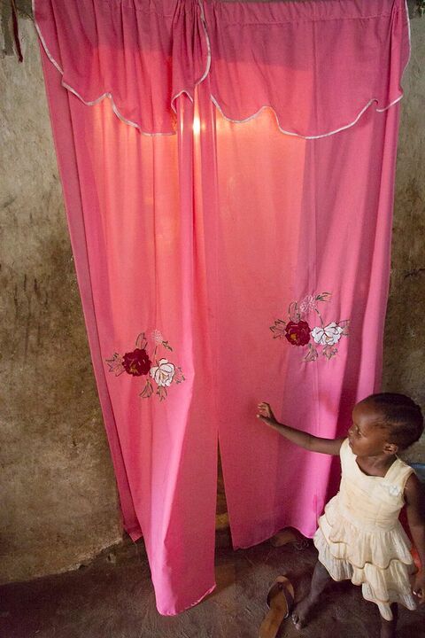 Small child beside a glowing pink curtain