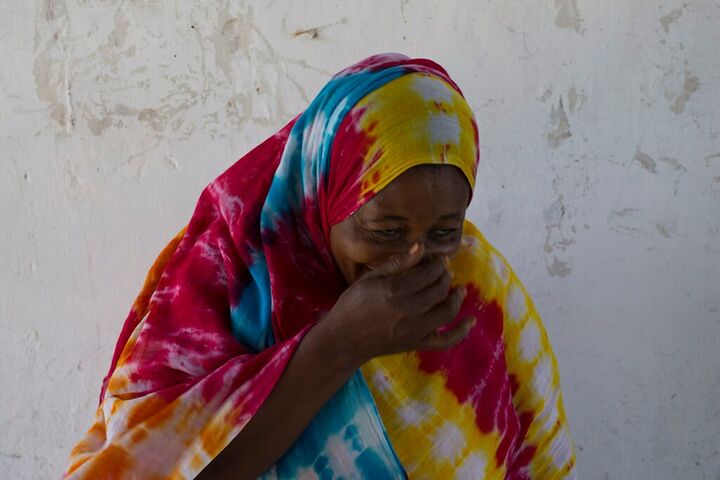 Woman in a rainbow scarf laughing behind her hand