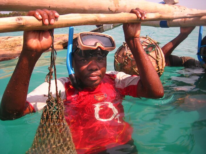 Boy in snorkel mask lifting a net from the water