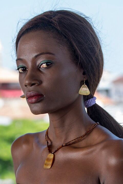 Young woman with gold earrings above the rooftops of Stone Town