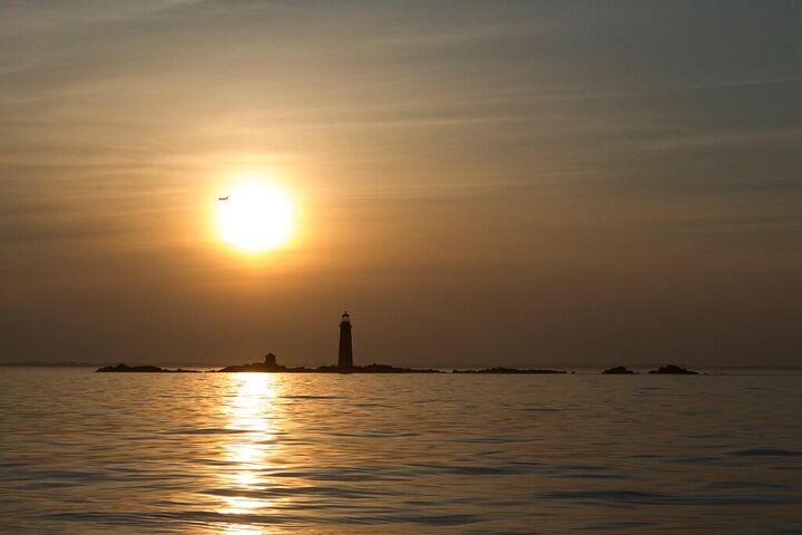 Sun setting over the sea behind a lighthouse