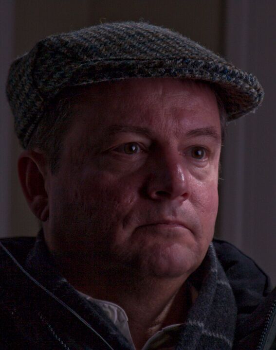 Man in a tweed cap in soft window light